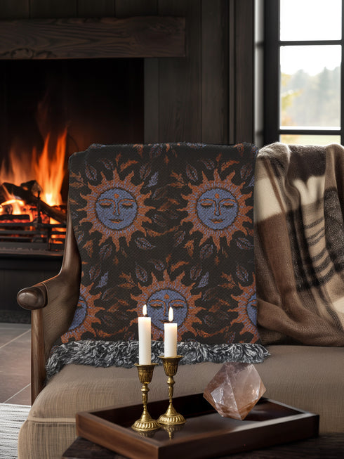 Luxurious woven cotton throw blanket featuring mystical blue sun faces with copper rays on black background, bordered by elegant fringe. Perfect celestial wall hanging, witchy bedroom decor, or dark academia throw for couch or bed.